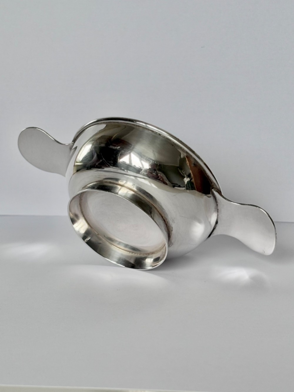 A shallow sterling silver Scottish quaich featuring two flat lug handles and engraved Gaelic lettering in the centre bowl. View VII