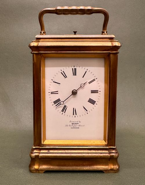 fig 1. A Victorian gilt brass carriage clock with a white enamel dial next to its leather travelling box and double-ended winding key.