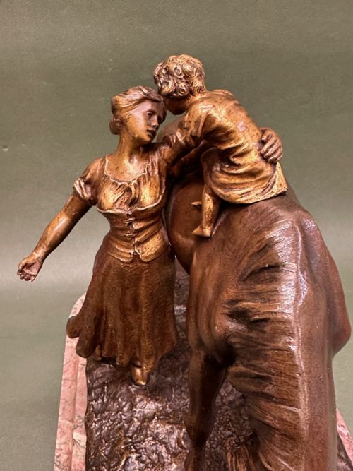 fig 2. A patinated bronze sculpture depicting a mother and child standing beside a horse drinking from a trough, mounted on a pink veined marble base.