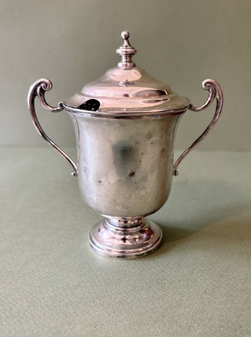 fig 1. An antique silver two-handled cup featuring a fitted domed lid with a turned finial and a stepped pedestal foot.