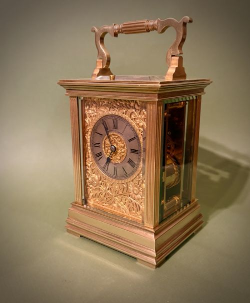 fig 1. A gilt brass French repeating carriage clock with fluted corner columns, a silvered chapter ring, and a floral chased face.