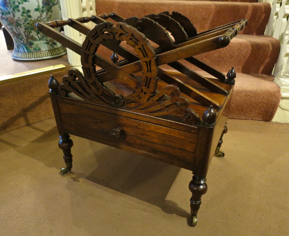 A Regency rosewood canterbury featuring pierced carved music dividers, corner finials, a lower drawer, and turned legs on brass castors. View III