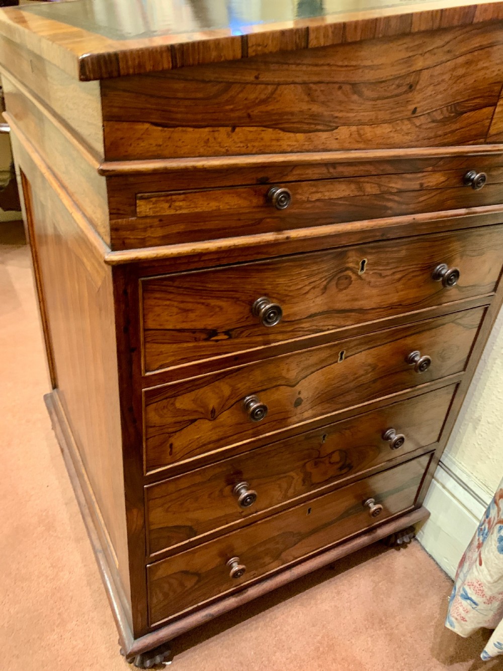 An antique rosewood Davenport desk featuring a sloped leather writing surface, top brass gallery, and side drawers with turned wooden knobs. View V