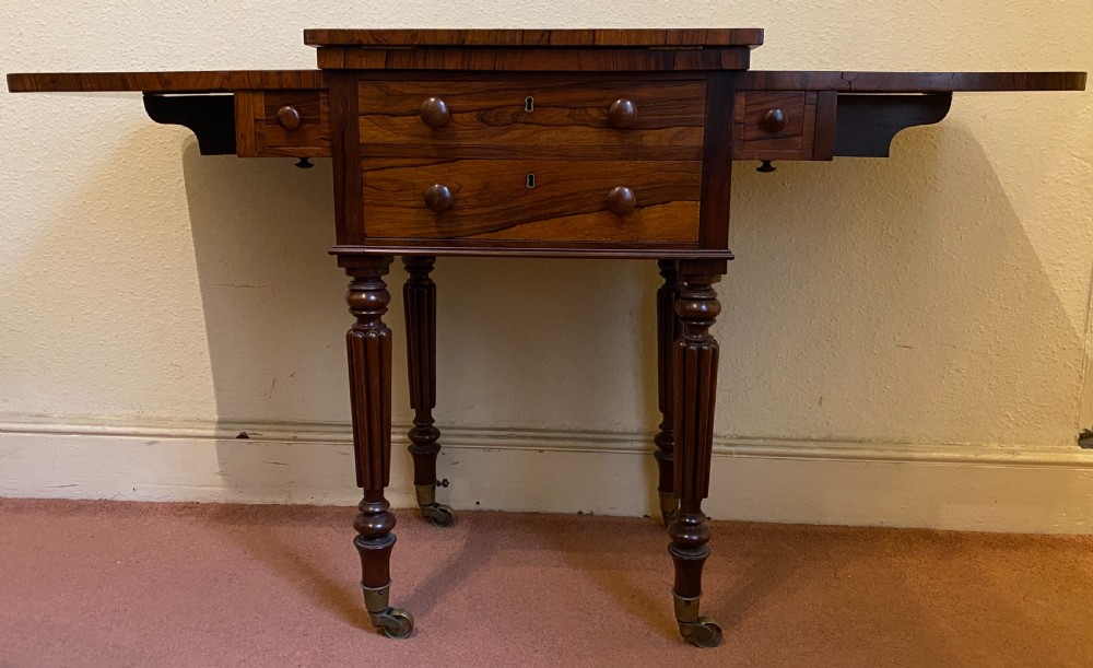 A William IV rosewood writing and work table featuring an adjustable leather-inset writing slope, drop-leaf sides, two drawers, and reeded turned legs on brass castors. View II