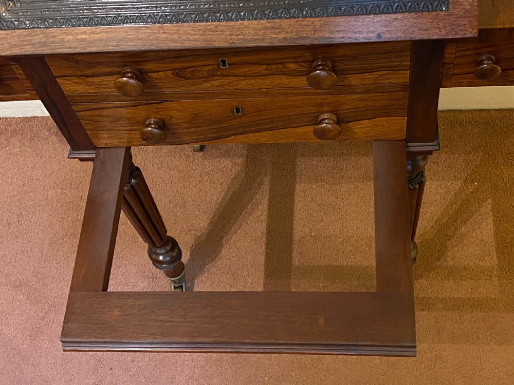 A William IV rosewood writing and work table featuring an adjustable leather-inset writing slope, drop-leaf sides, two drawers, and reeded turned legs on brass castors. View XV