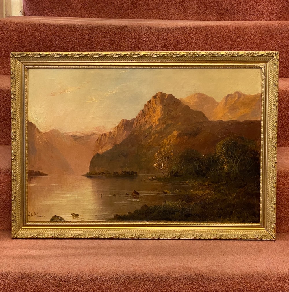 A Victorian oil painting on canvas by Gustave De Breanski depicting a mountainous lake view at sunrise in an ornate gilt frame.