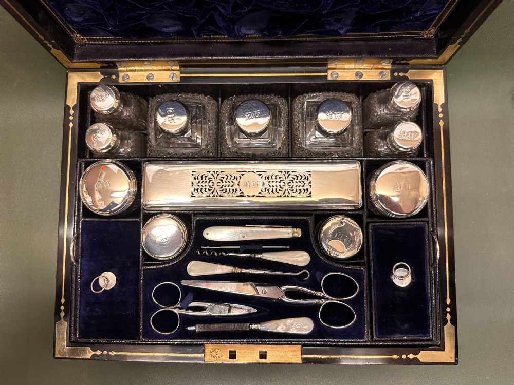 An open 19th-century kingwood dressing case with brass inlay, lined in blue velvet and fitted with silver-topped glass bottles, silver containers, and manicure tools. View III