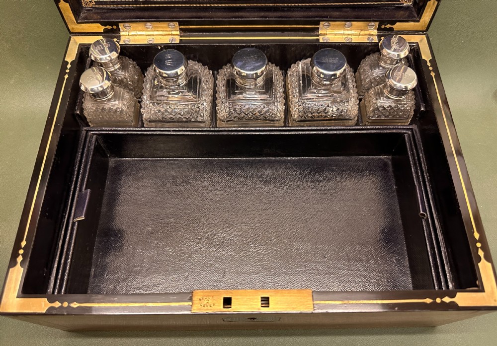 An open 19th-century kingwood dressing case with brass inlay, lined in blue velvet and fitted with silver-topped glass bottles, silver containers, and manicure tools. View V