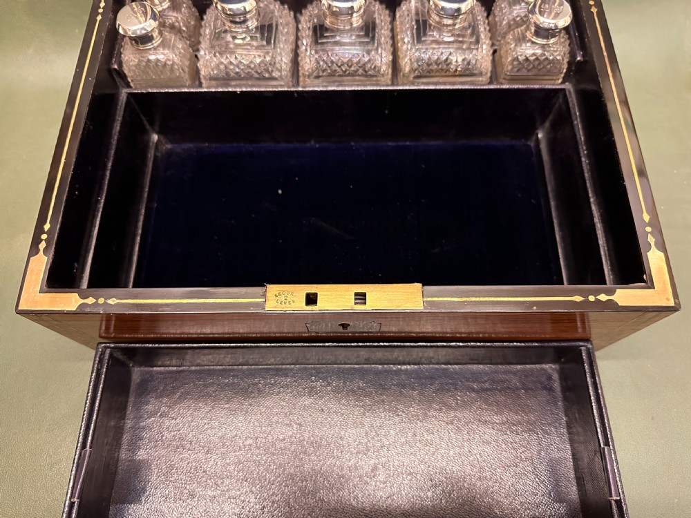 An open 19th-century kingwood dressing case with brass inlay, lined in blue velvet and fitted with silver-topped glass bottles, silver containers, and manicure tools. View VII