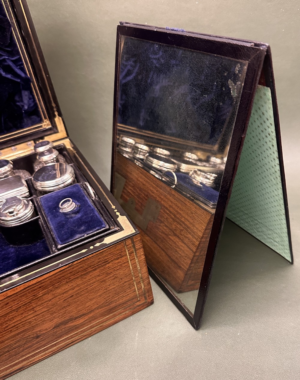 An open 19th-century kingwood dressing case with brass inlay, lined in blue velvet and fitted with silver-topped glass bottles, silver containers, and manicure tools. View XVI