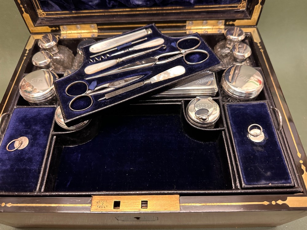 An open 19th-century kingwood dressing case with brass inlay, lined in blue velvet and fitted with silver-topped glass bottles, silver containers, and manicure tools. View XVIII