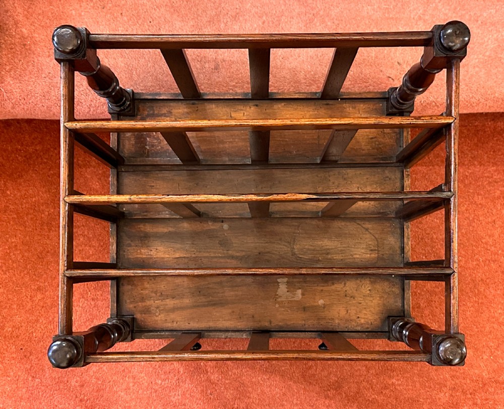 A 19th-century mahogany music Canterbury featuring four divided compartments, turned corner posts with finials, a single lower drawer with wooden knobs, and turned legs on brass castors. View XI