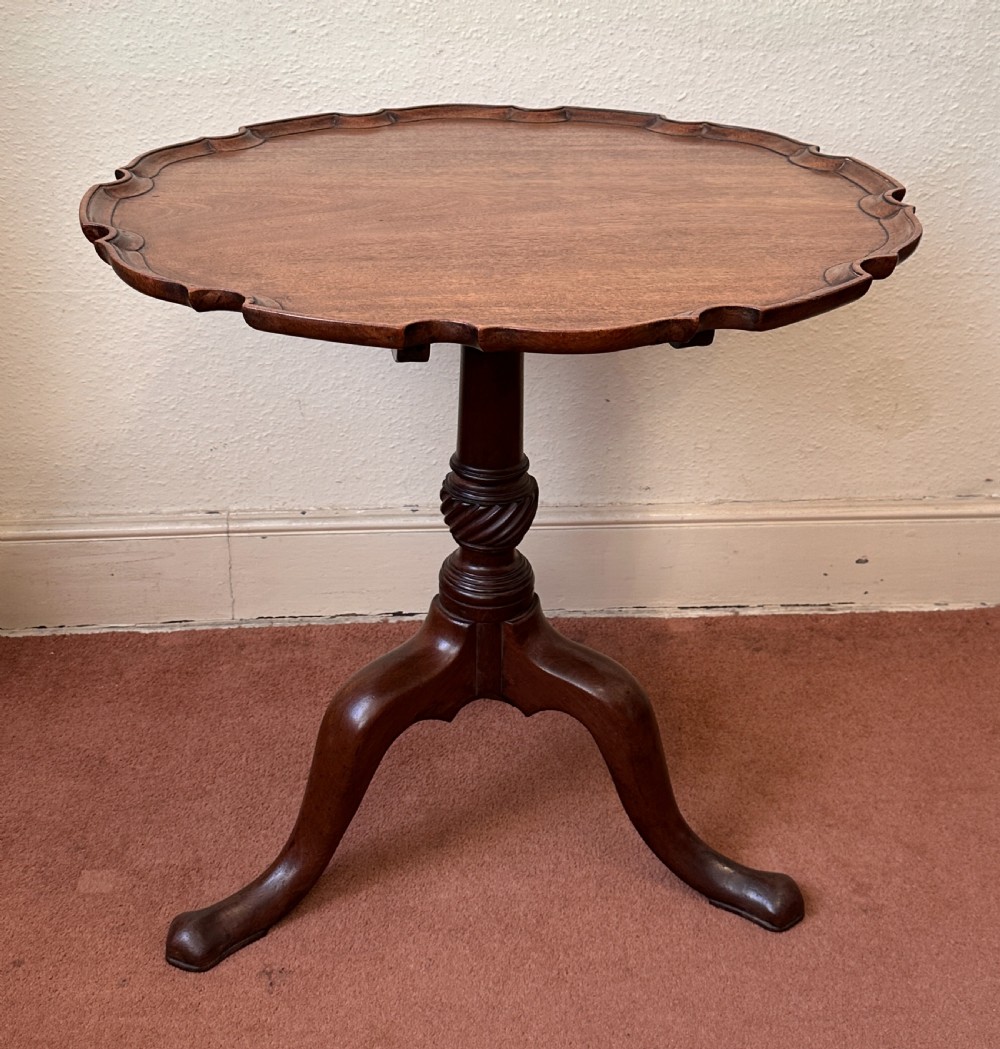 A mid-19th century mahogany occasional table with a scalloped piecrust rim, spiral-turned central column, and tripod cabriole legs.