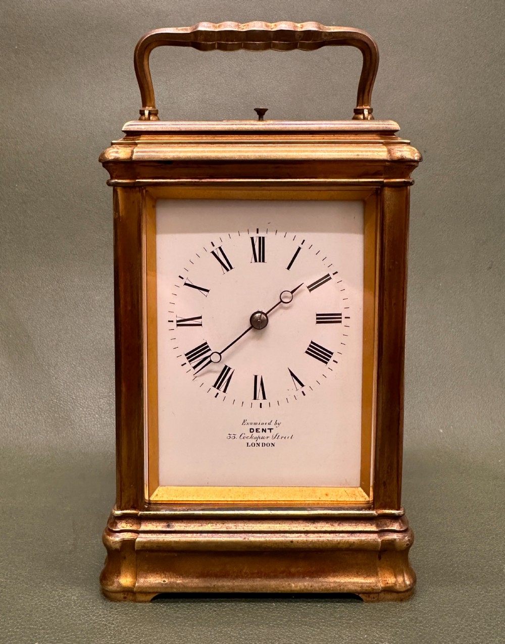 A Victorian gilt brass carriage clock with a white enamel dial next to its leather travelling box and double-ended winding key. View II