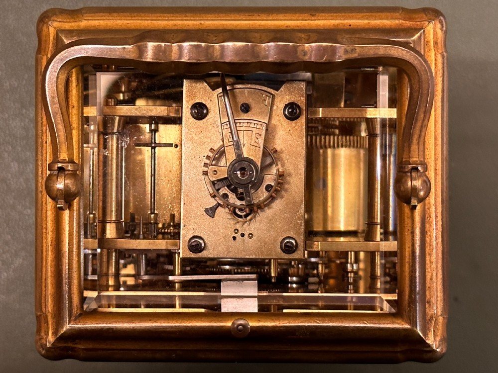 A Victorian gilt brass carriage clock with a white enamel dial next to its leather travelling box and double-ended winding key. View XIV