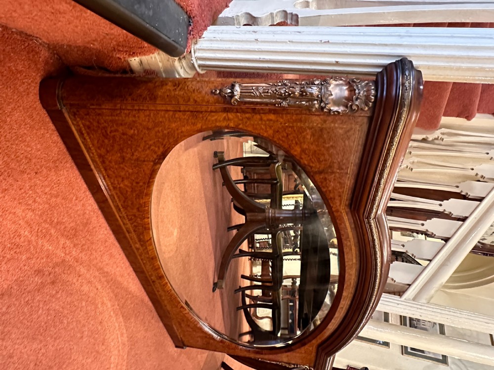 A late nineteenth-century horizontal burr yew-wood overmantel mirror featuring an oval bevelled glass plate, domed top rail, and gilt ormolu side mounts. View V