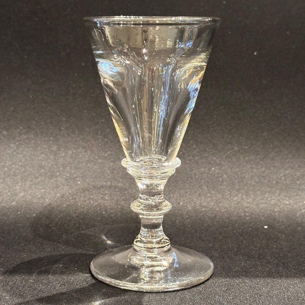A clear Victorian lead glass toastmaster goblet with a thick deceptive bowl, a knopped stem, and a circular flat foot.