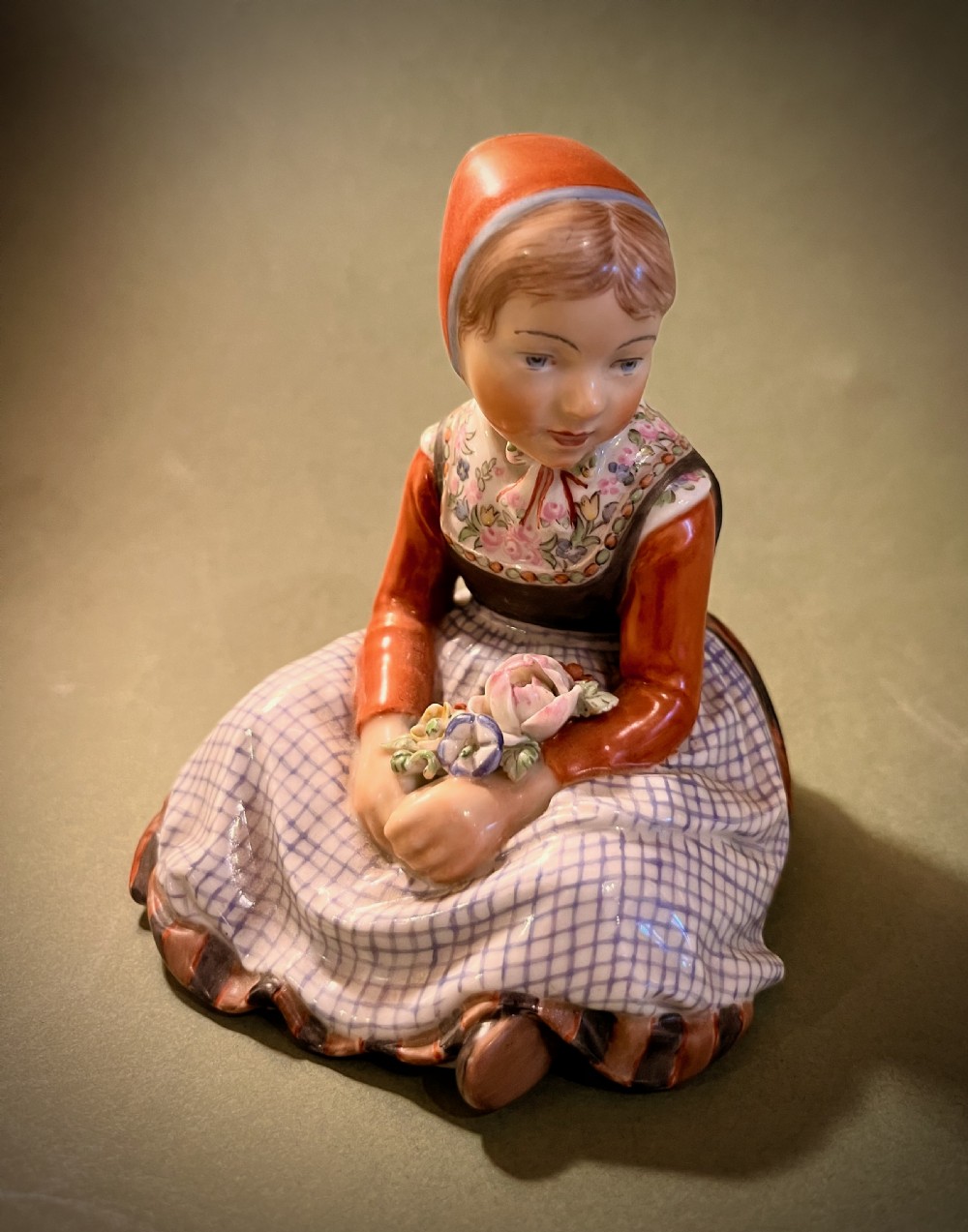 A set of ten hand-painted Royal Copenhagen porcelain figurines depicting seated children wearing traditional Danish regional costumes and floral garlands. View II