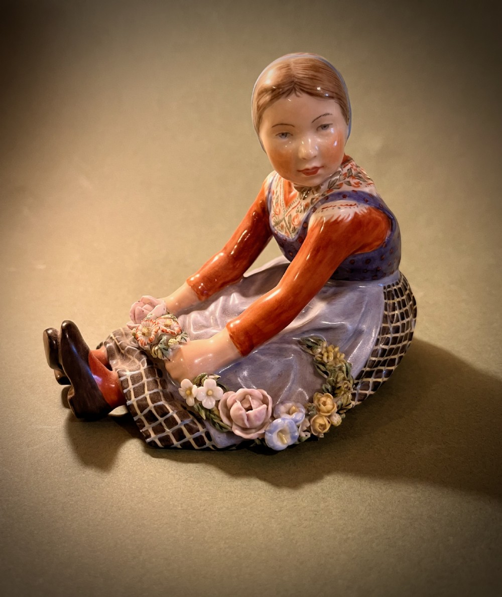 A set of ten hand-painted Royal Copenhagen porcelain figurines depicting seated children wearing traditional Danish regional costumes and floral garlands. View III