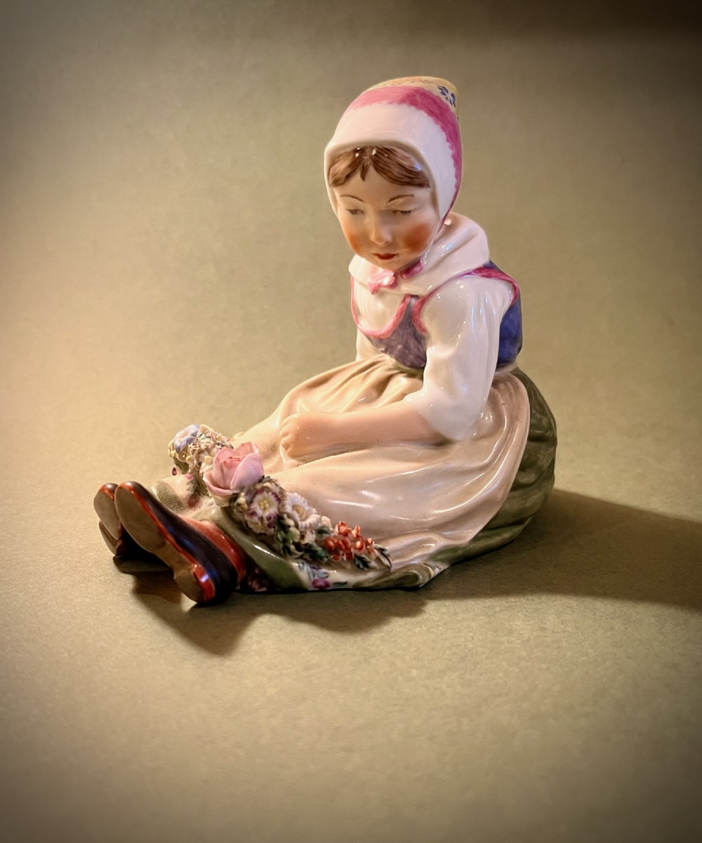 A set of ten hand-painted Royal Copenhagen porcelain figurines depicting seated children wearing traditional Danish regional costumes and floral garlands. View V
