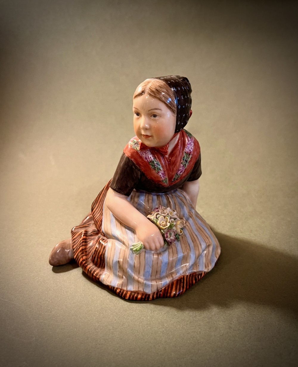 A set of ten hand-painted Royal Copenhagen porcelain figurines depicting seated children wearing traditional Danish regional costumes and floral garlands. View VIII
