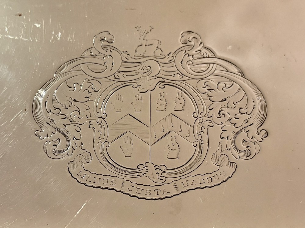 An oval Old Sheffield plate serving tray featuring two handles, a gadrooned rim with shell motifs, and an engraved armorial crest in the centre. View VI