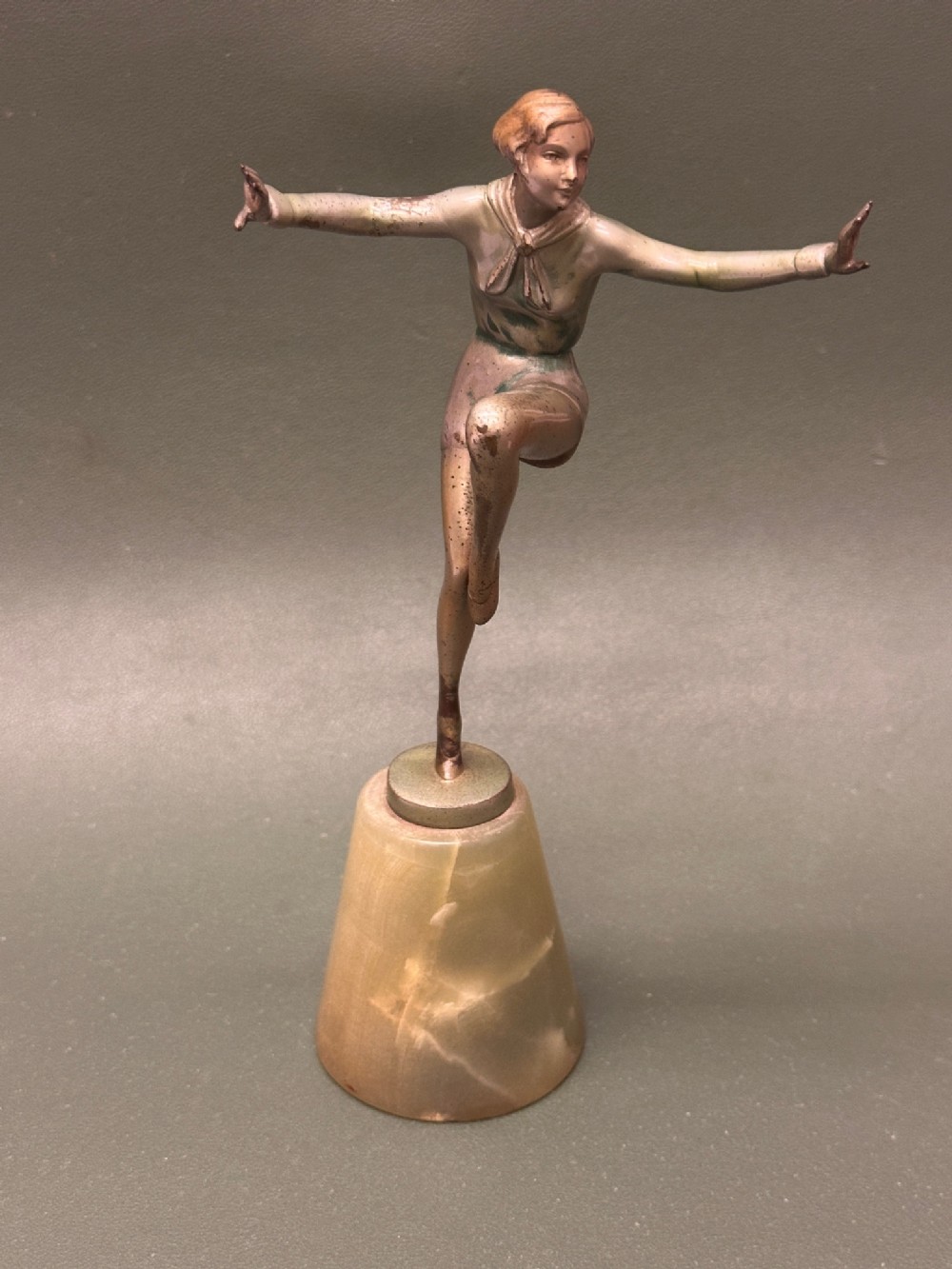 An Art Deco cold-painted bronze figure of a female dancer in motion, mounted on a tapered onyx plinth base.