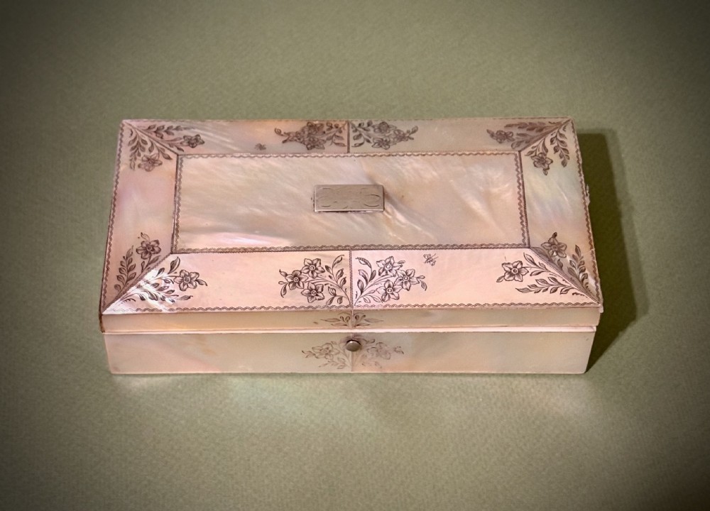 An open rectangular mother-of-pearl sewing box lined with deep green velvet, featuring a removable tray filled with fitted metal and nacre needlework tools. View II