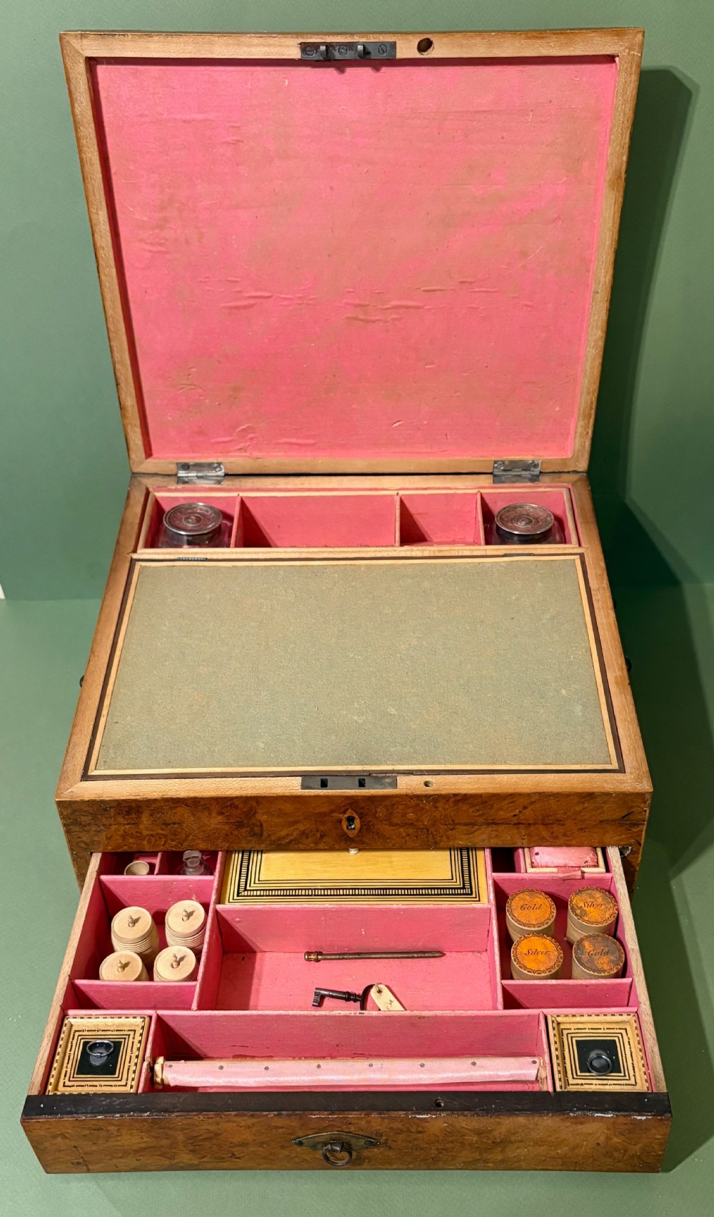 A square Regency burr walnut workbox with a central classical medallion print, decorative printed border, brass side handles, and a lower drawer. View II