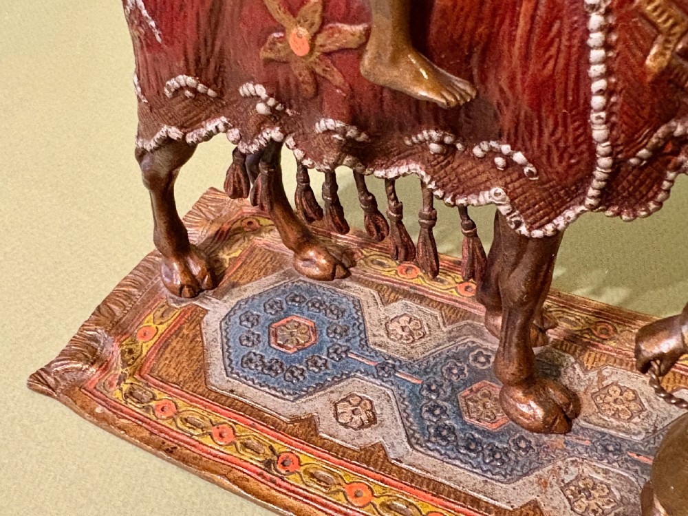 A cold-painted Vienna bronze group depicting a camel musician playing drums led by a standing figure on a cast bronze carpet base. View III