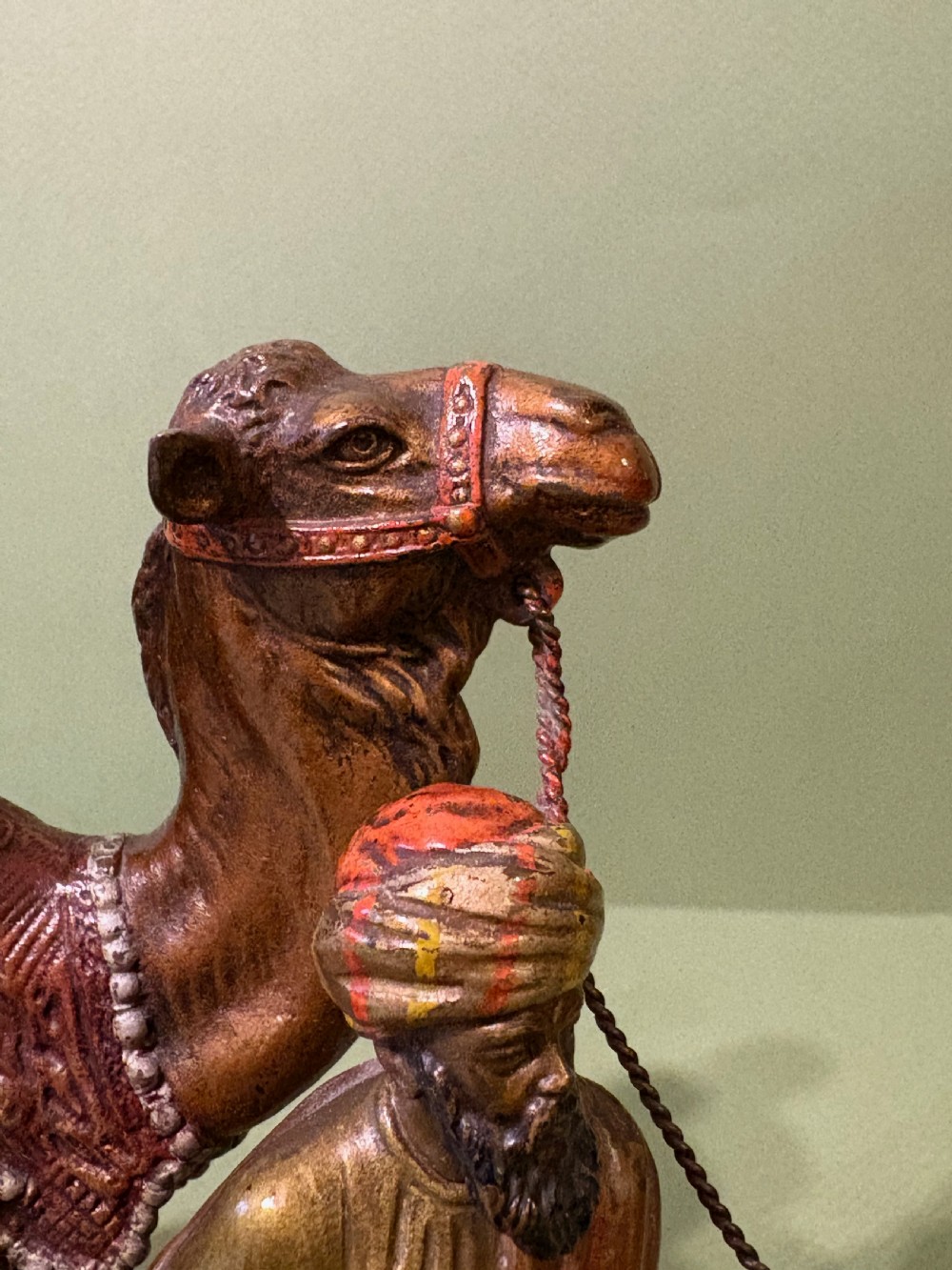 A cold-painted Vienna bronze group depicting a camel musician playing drums led by a standing figure on a cast bronze carpet base. View IV