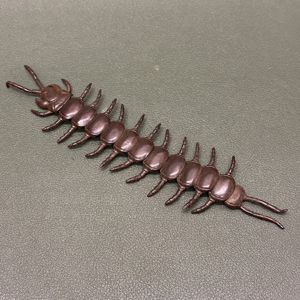 A detailed 19th-century Japanese Meiji period bronze articulated centipede resting on a neutral textured surface.