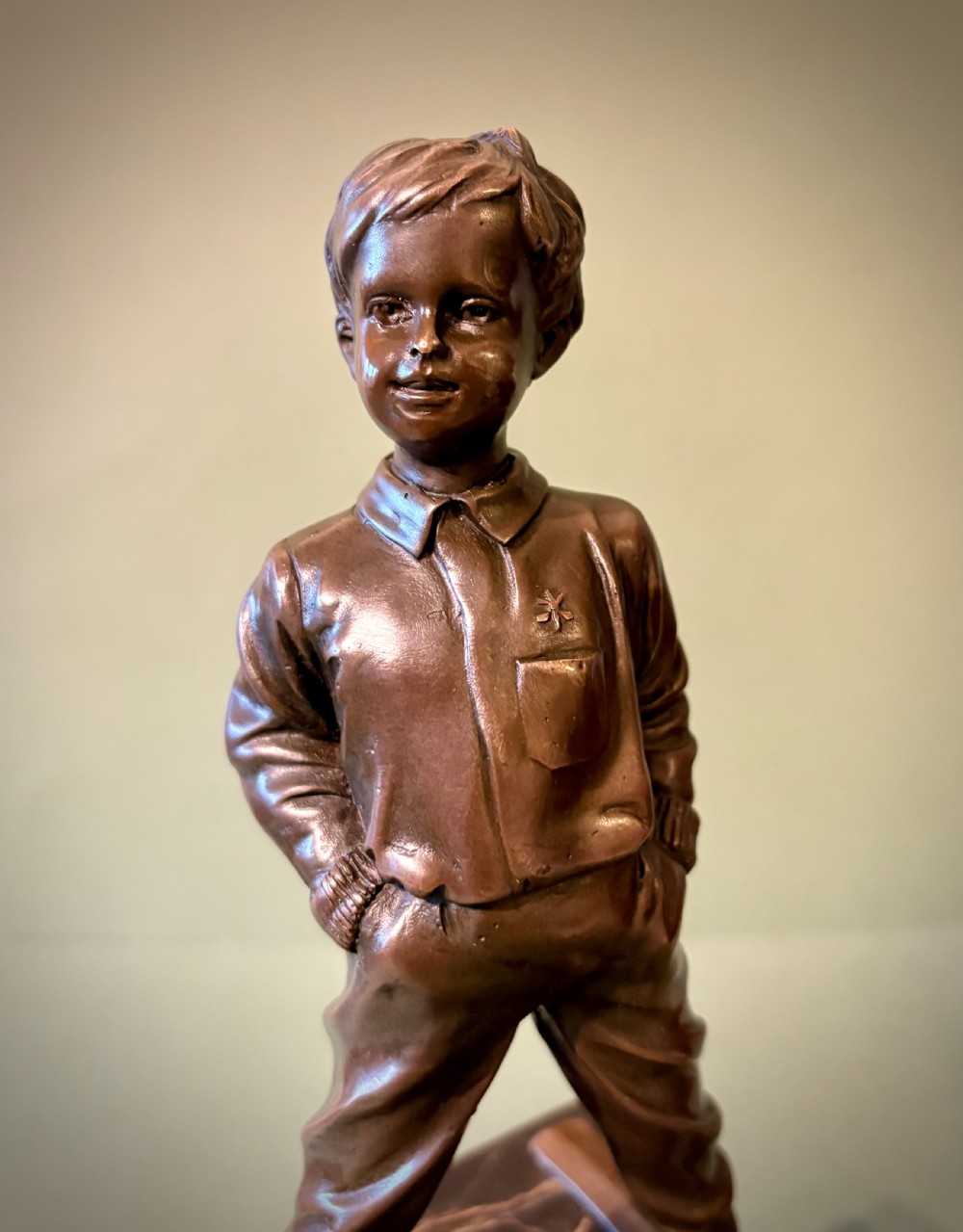 A dark bronze figurine depicting a young boy on skis mounted on a heavy, reddish-brown veined marble plinth. View II