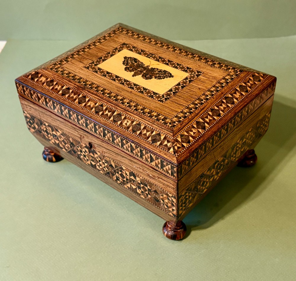 An open Victorian rosewood sewing box featuring geometric Tunbridge ware mosaic inlay, a pink silk interior, and fitted compartments containing sewing tools. View II