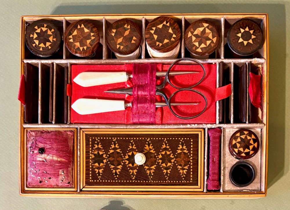 An open Victorian rosewood sewing box featuring geometric Tunbridge ware mosaic inlay, a pink silk interior, and fitted compartments containing sewing tools. View IV