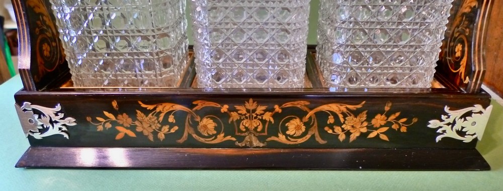 A Victorian three-bottle cut crystal decanter tantalus housed in a dark wooden frame with floral marquetry inlay and a silver-toned metal locking top handle. View III