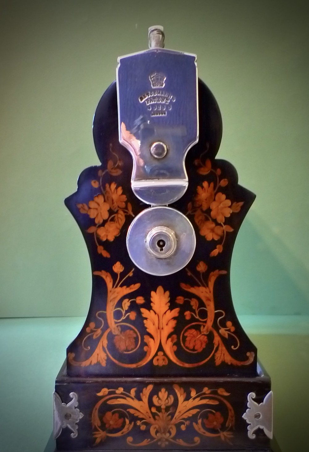 A Victorian three-bottle cut crystal decanter tantalus housed in a dark wooden frame with floral marquetry inlay and a silver-toned metal locking top handle. View V