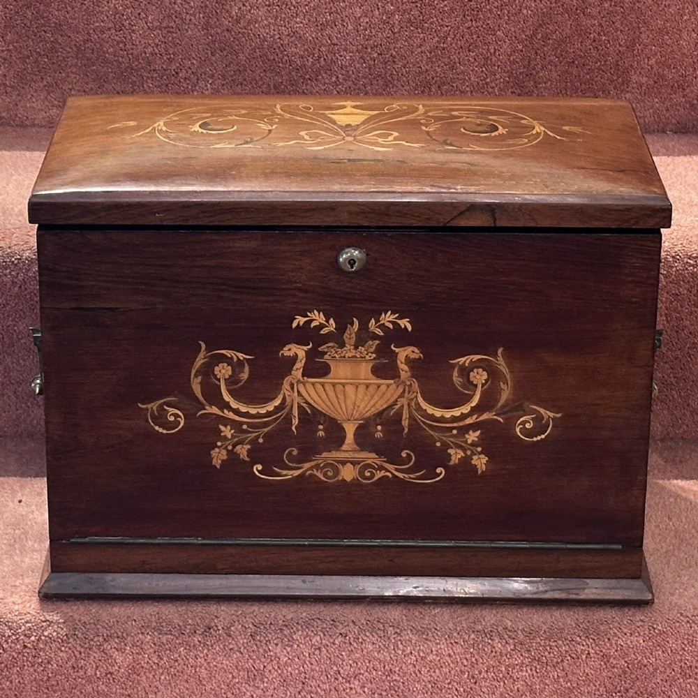 A rectangular dark rosewood writing box featuring central satinwood marquetry of an urn with foliate scrolls and a central brass keyhole escutcheon.