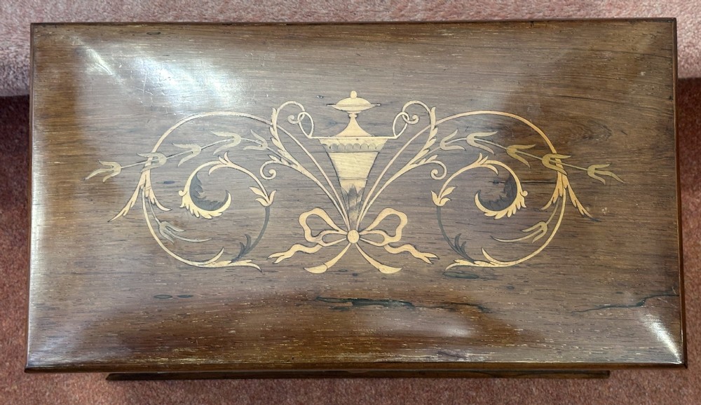 A rectangular dark rosewood writing box featuring central satinwood marquetry of an urn with foliate scrolls and a central brass keyhole escutcheon. View XI