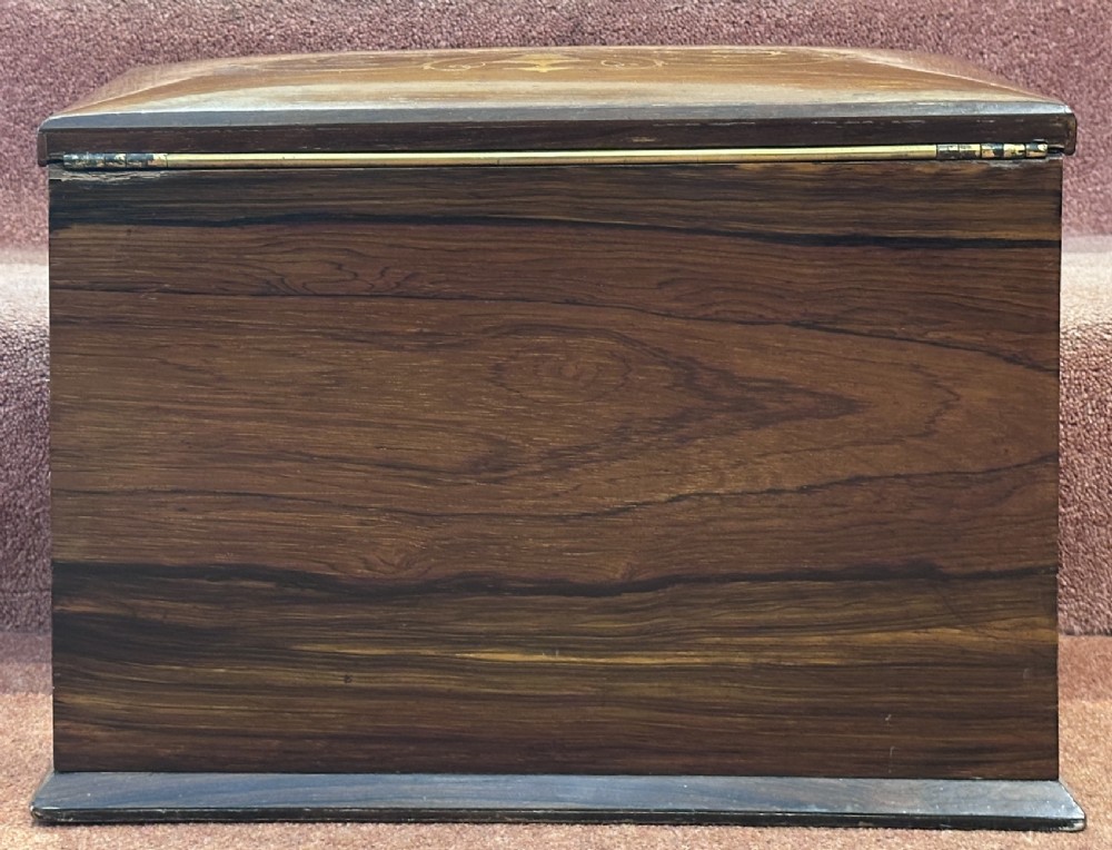 A rectangular dark rosewood writing box featuring central satinwood marquetry of an urn with foliate scrolls and a central brass keyhole escutcheon. View XIV