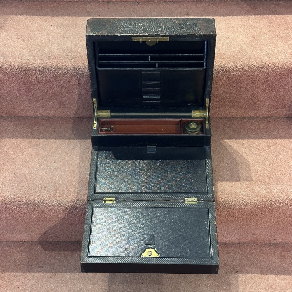 An open Victorian leather-bound writing box featuring internal letter slots, a pen tray, an inkwell compartment, and brass hardware. View III