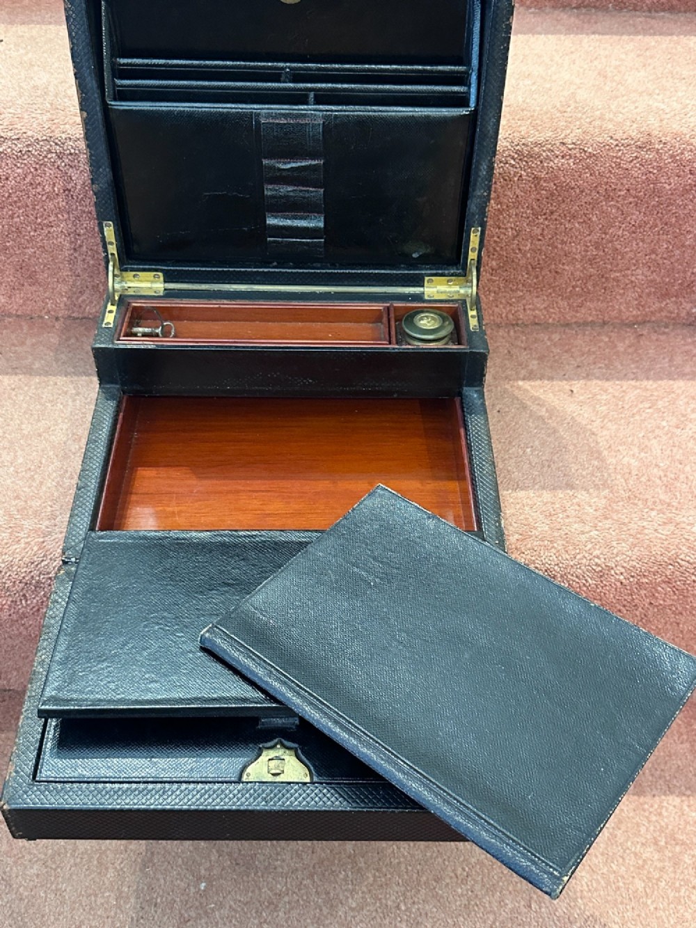 An open Victorian leather-bound writing box featuring internal letter slots, a pen tray, an inkwell compartment, and brass hardware. View VI