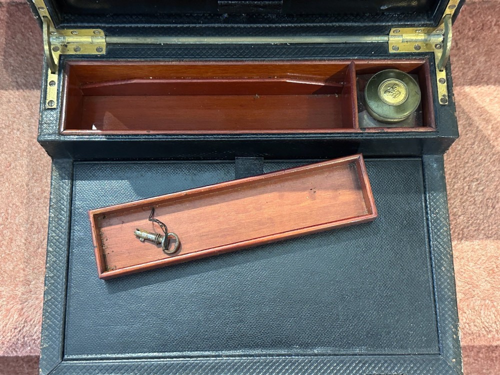 An open Victorian leather-bound writing box featuring internal letter slots, a pen tray, an inkwell compartment, and brass hardware. View VII