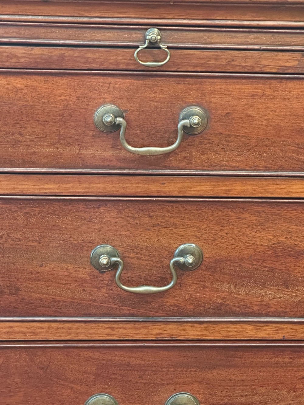 An 18th-century George III mahogany bachelors chest featuring four graduated drawers, brass swan-neck handles, a pull-out brushing slide, and bracket feet. View IV
