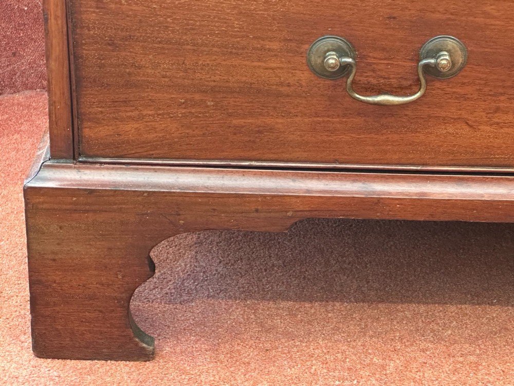 An 18th-century George III mahogany bachelors chest featuring four graduated drawers, brass swan-neck handles, a pull-out brushing slide, and bracket feet. View V