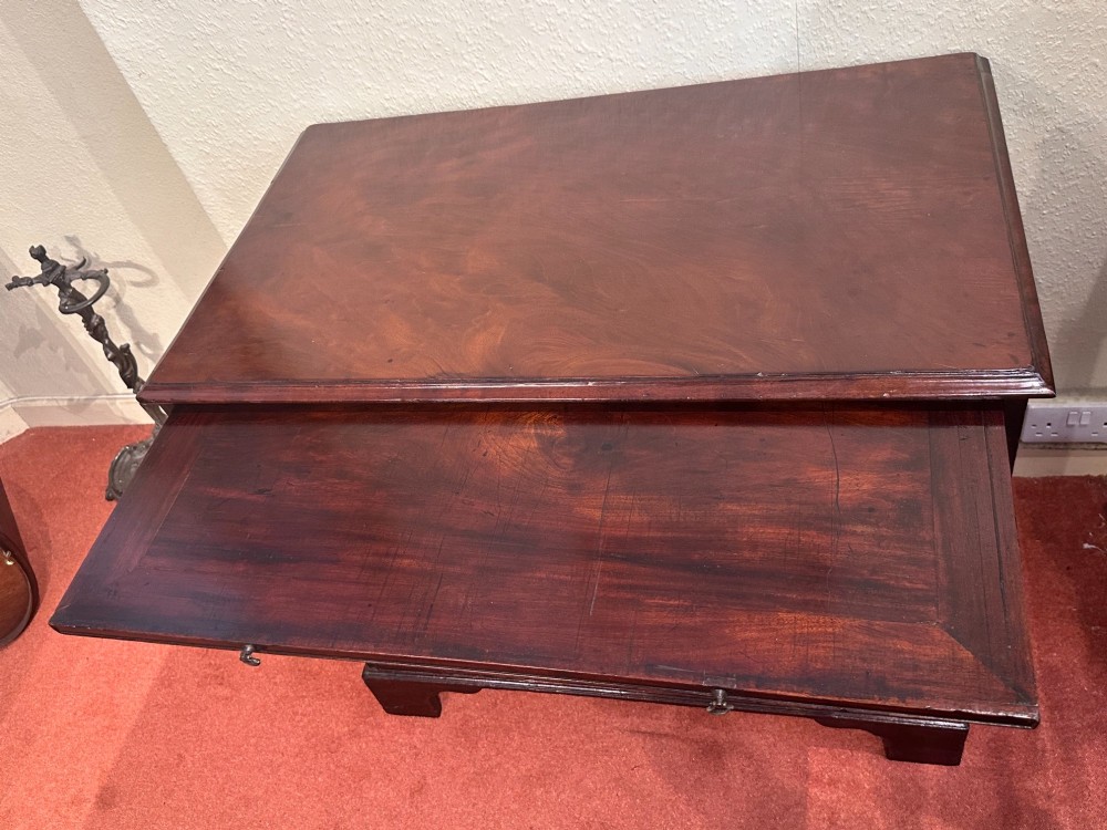 A George III dark mahogany bachelors chest featuring four graduated drawers, brass swan-neck handles, keyhole escutcheons, a pull-out brushing slide, and bracket feet. View V