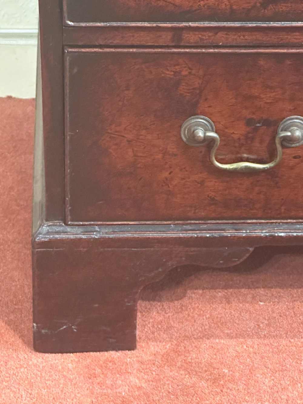 A George III dark mahogany bachelors chest featuring four graduated drawers, brass swan-neck handles, keyhole escutcheons, a pull-out brushing slide, and bracket feet. View IX