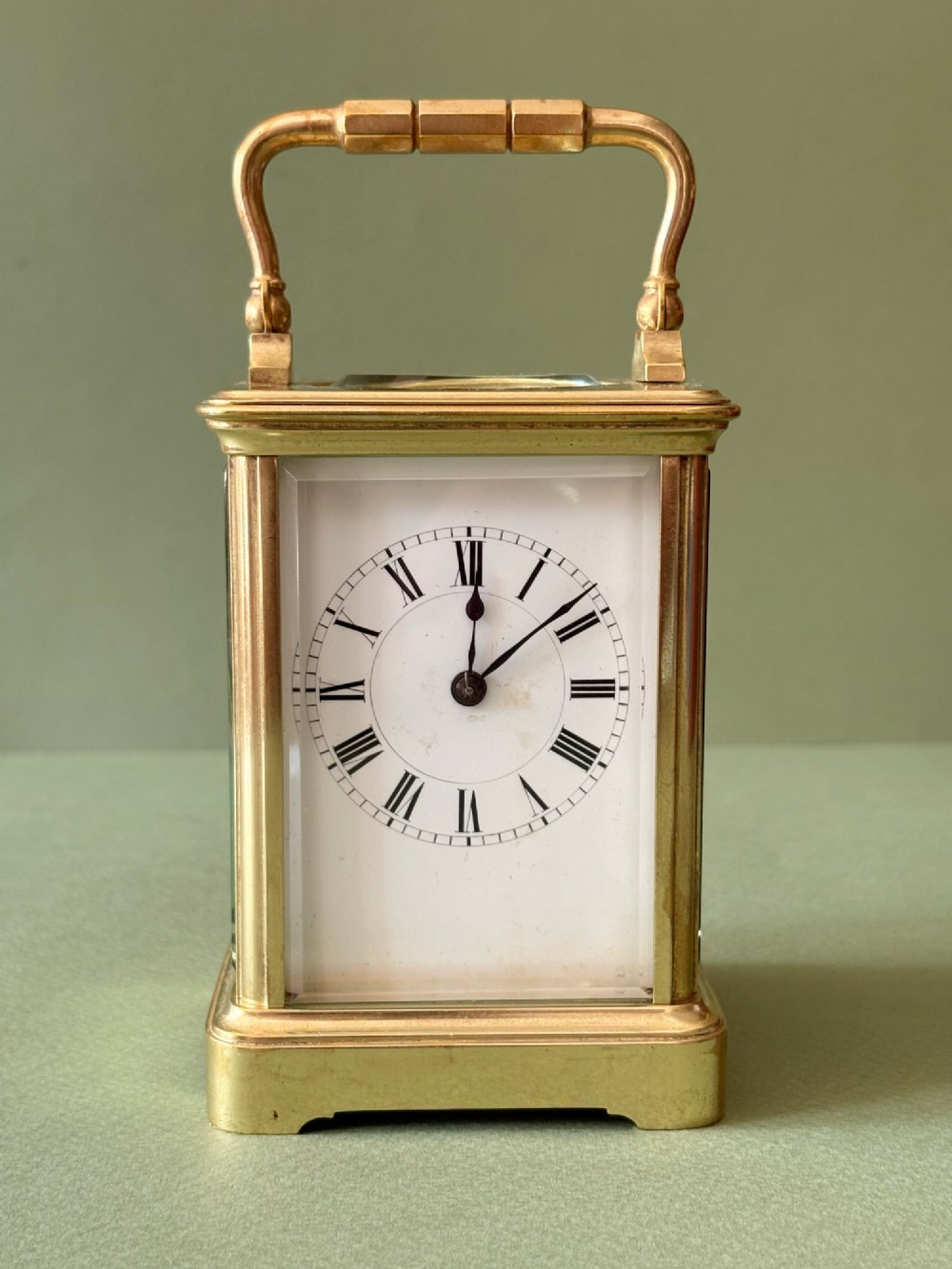 A nineteenth-century French carriage clock featuring a gilt brass case, glass side panels, a hinged top handle, and a white enamel dial with black Roman numerals.
