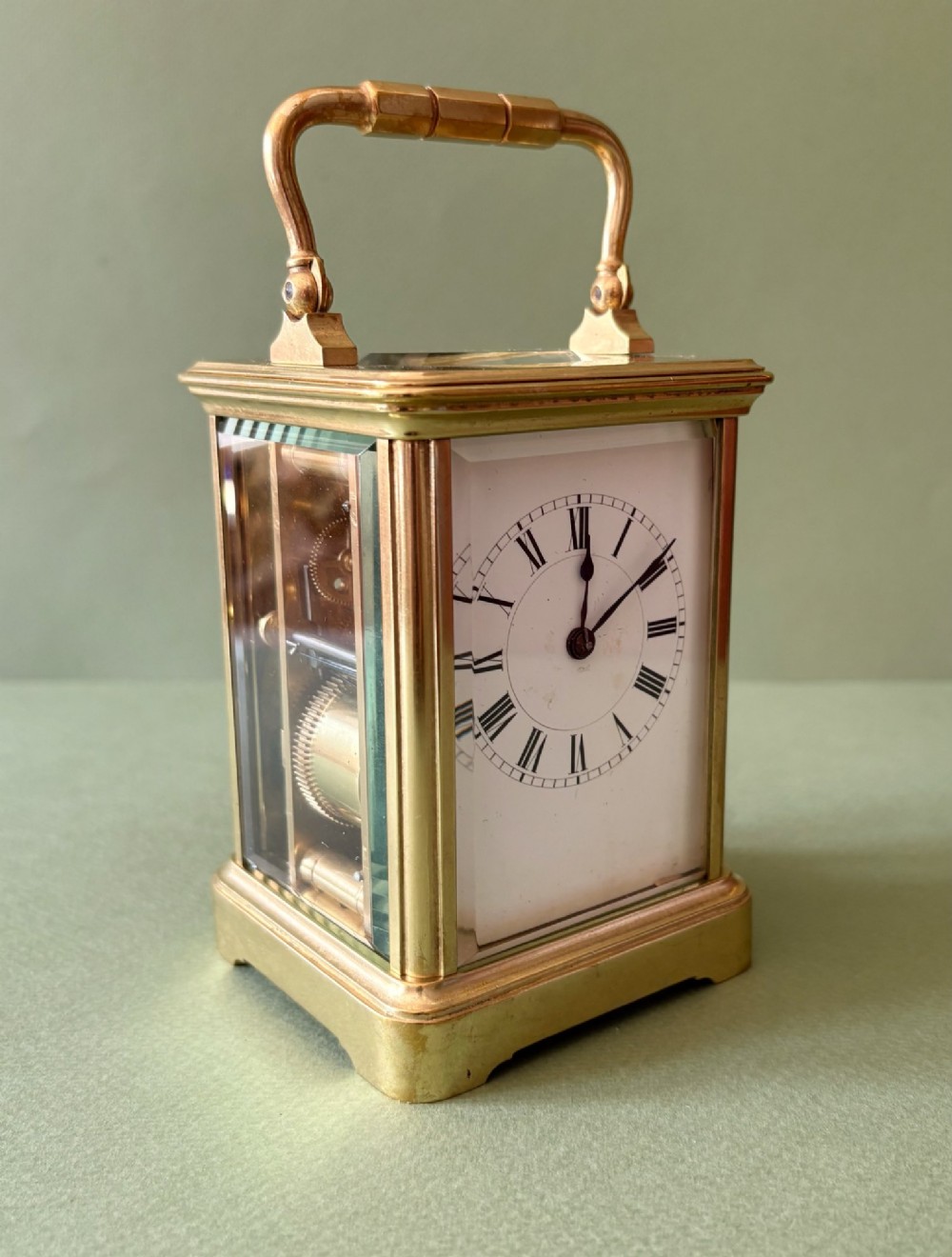 A nineteenth-century French carriage clock featuring a gilt brass case, glass side panels, a hinged top handle, and a white enamel dial with black Roman numerals. View II