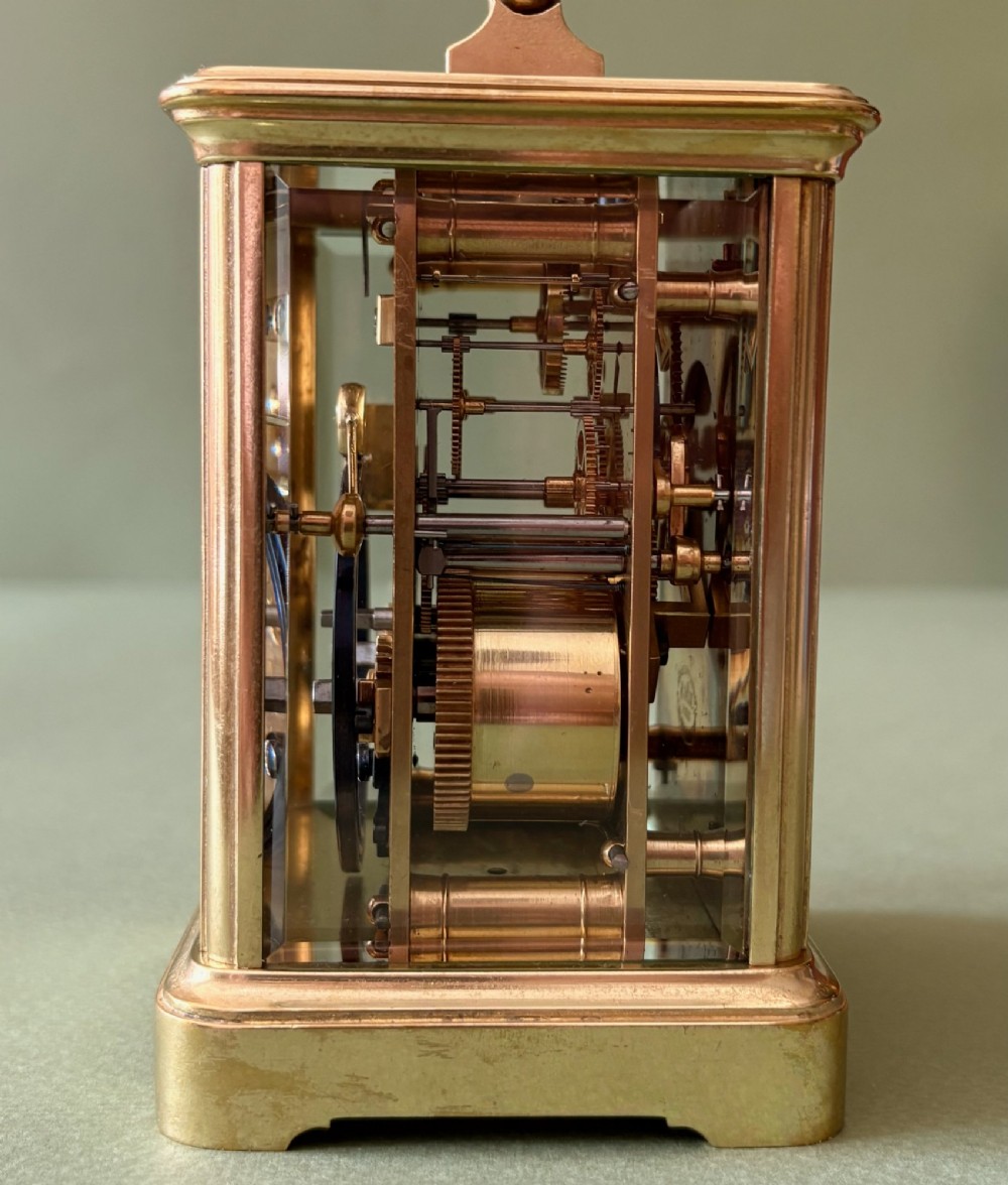 A nineteenth-century French carriage clock featuring a gilt brass case, glass side panels, a hinged top handle, and a white enamel dial with black Roman numerals. View V